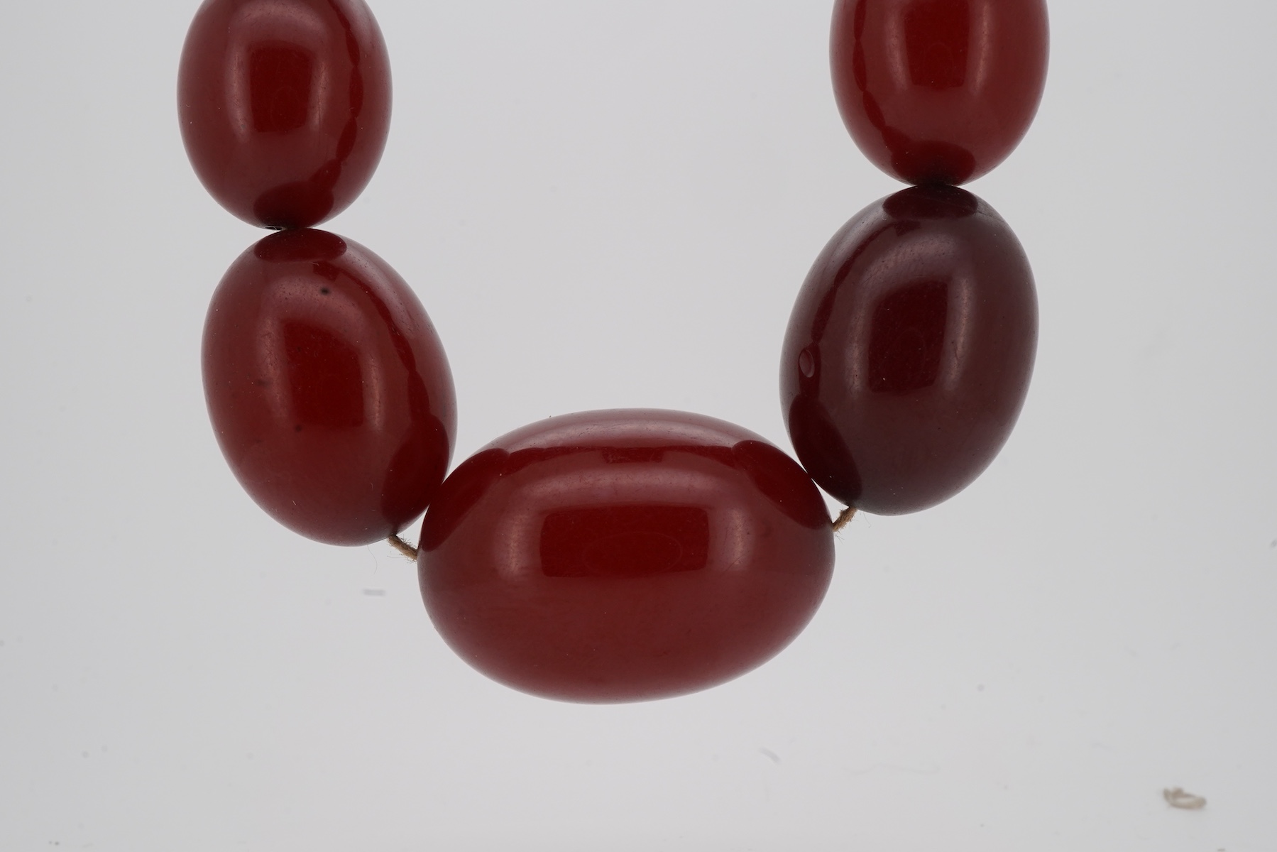 A cherry-coloured bakelite simulant amber necklace, composed of graduated beads measuring approximately 8-28mm, length 86cm, gross weight approximately 61 grams